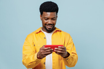 Young gambling man of African American ethnicity wear yellow shirt using play racing app on mobile...