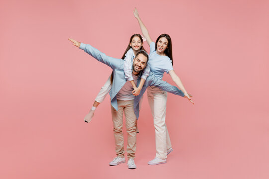 Full Body Young Parents Mom Dad With Child Kid Daughter Teen Girl In Blue Clothes Give Piggyback Ride To Kid Sit On Back Stretch Arms Isolated On Plain Pastel Light Pink Background Family Day Concept.