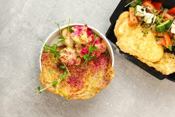 Healthy food delivery concept. Beef schnitzel with cauliflower in an eco paper container on a gray...