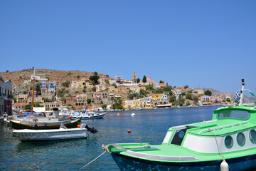 Fototapeta na wymiar greek island with colored boats and houses on blue sky background