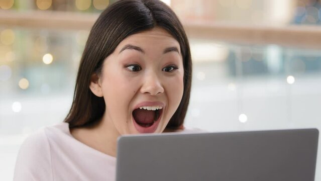 Overjoyed Asian woman wins achieves goal triumph says wow feels winner happy looking at laptop screen. Korean lady girl with computer receive job offer discounts event invite online victory close up