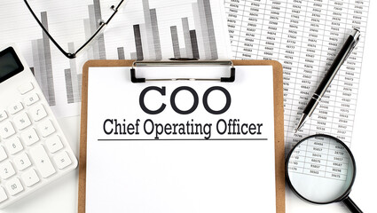 Paper with COO - Chief Operating Officer on a chart with calculator,pen and magnifier