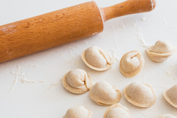 Uncooked homemade pelmeni on white table. Process of making pelmeni, ravioli or dumplings with meat