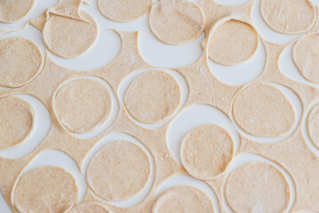 Dough for homemade pelmeni on white table. Process of making pelmeni, ravioli or dumplings with meat