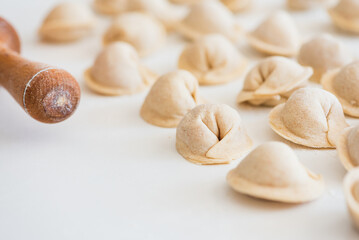 Fototapeta na wymiar Uncooked homemade pelmeni on white table. Process of making pelmeni, ravioli or dumplings with meat