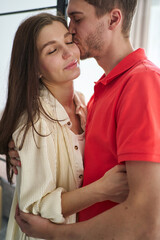 Naklejka premium young couple, a man gently kisses a woman, the concept of a happy young family, tenderness, home comfort, love and harmony in a couple