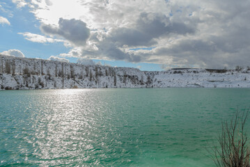 Martian turquoise lake in Crimea with a view of the snow-covered slopes