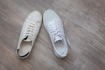 Pair of trendy new and old white shoes on light wooden background, top view. High quality photo