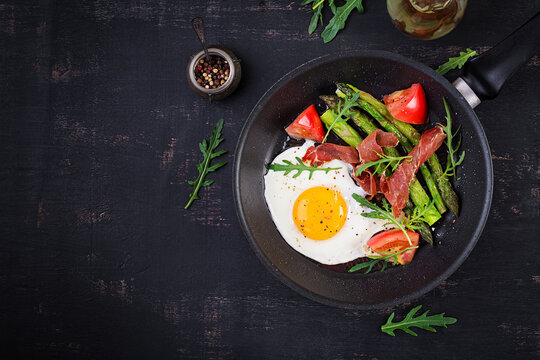 Fried egg with asparagus, tomato and bacon. Useful breakfast. Top view, overhead