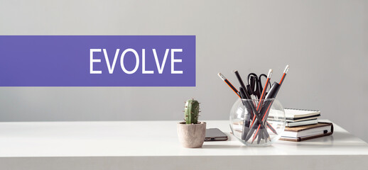 EVOLVE word written in a violet strip on office desk background, business concept