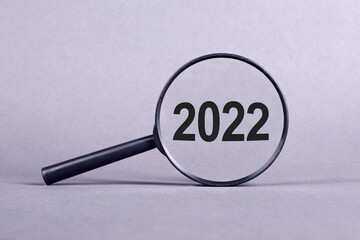 Text 2022 through magnifying glass on a light grey background