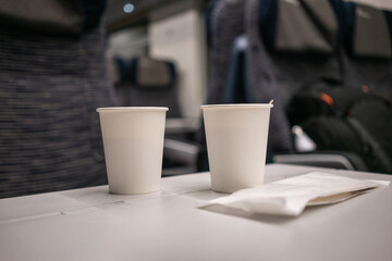 White paper disposable cup with coffee and wooden stick on the table on the train. High quality photo