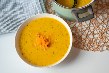 Creamy carrot soup in plate and in pot.