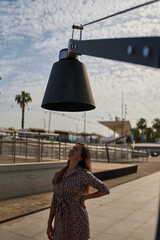 portrait of a young woman under a sculpture of a lamp in malaga on a hot sunny summer day