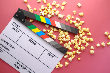 Movie clapper board and popcorn on table top view 