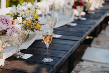 glass of champagne on a wooden table at an open air party.