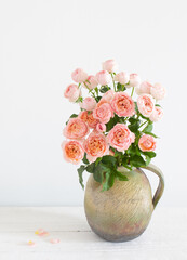 bouquet of peony roses in ceramic jug on white background