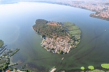 Small island with village, townhomes, forest, boats and yachts in the middle of lake. Drone view, aerial view, top view