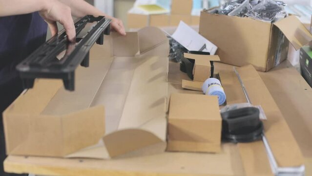 The worker puts the goods in a box for sending to the client. Packing plastic parts in a box.