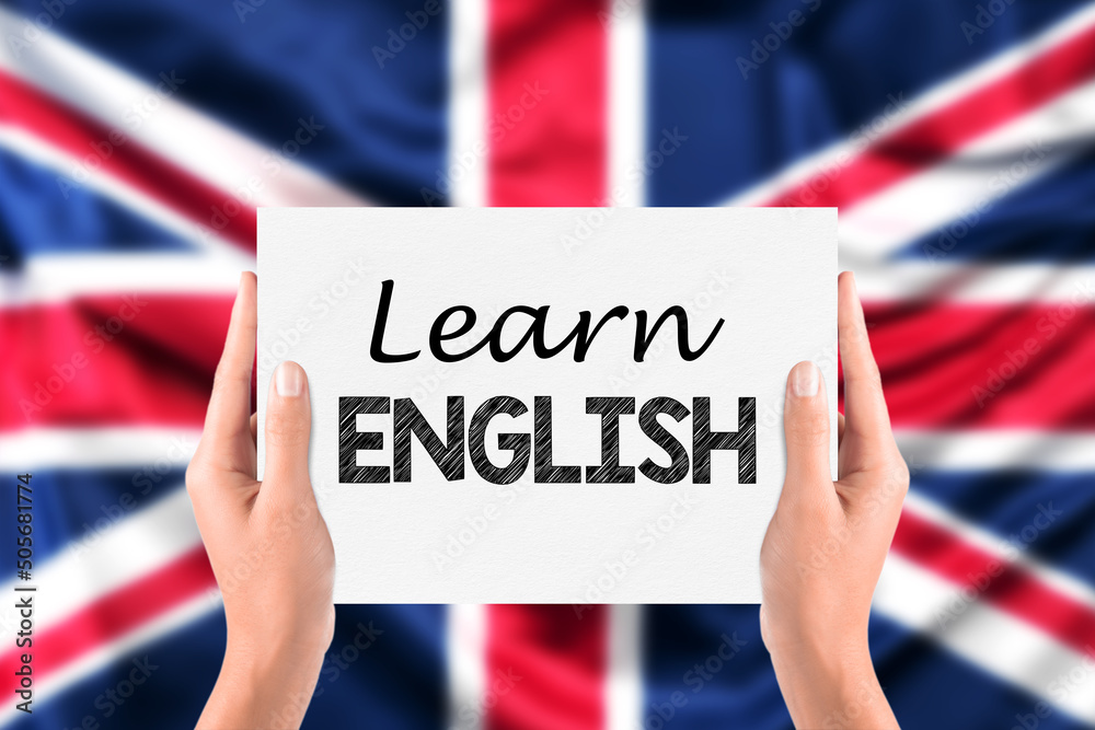 Wall mural english learning concept. learn english written on a paper card in hands with blurred united kingdom