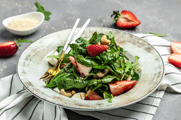 Strawberry salad with spinach, nuts, cheese, Fresh vegetarian salad on gray stone background, Food recipe background. Close up