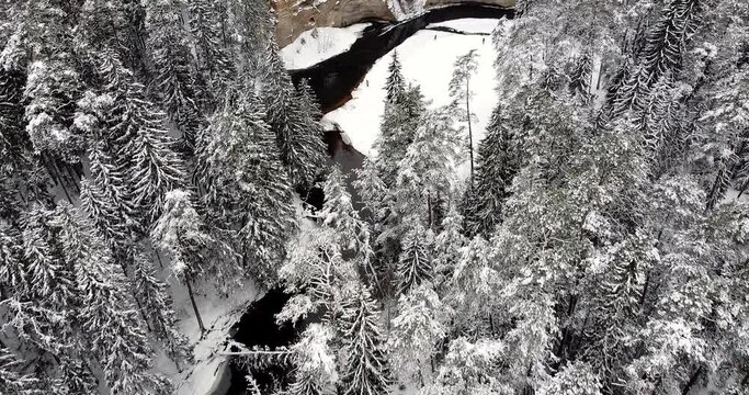 Overlooking Rocky outcrop in the winter landscape. Snow covered forest and river flowing through. Magical winter moment. Devonian sandstones, bedrock or ancient superficial deposits on the surface. 