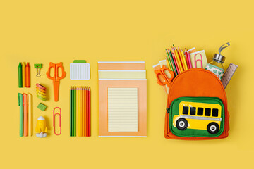 Kids Backpack with school bus on yellow background. Opened School backpack with stationery. Primary School or kindergarten.