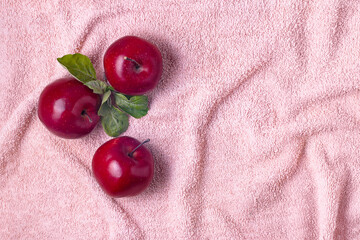 Top view of three apples and with green leaves on fur pink towel flat lay copy space.