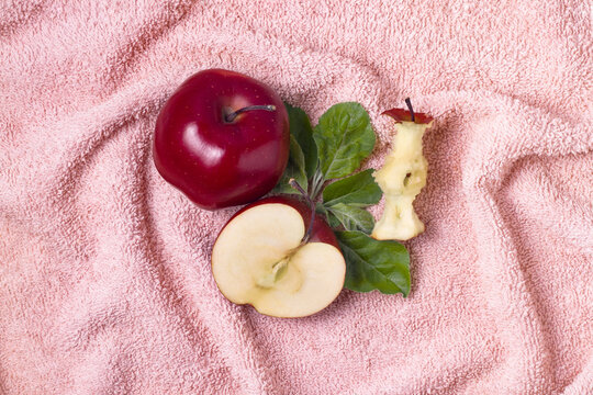 Top View Of Whole, Half Apple And Apple Core With Green Leaves On Fur Pink Towel Flat Lay.