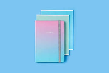 Planner and Notebooks in pastel color on blue background. School stationery or office supplies.