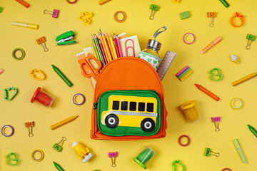 Kids Backpack with school bus on yellow background. Opened School backpack with stationery. Primary...