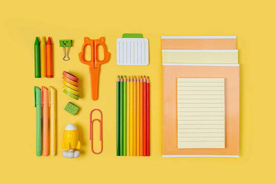 Kids stationery is arranged neatly on yellow background. Primary School stationery supplies. Workplace organization. Concept back to school.