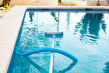 a swimming pool without people with a hose and a mop a vacuum cleaner for cleaning the pool...