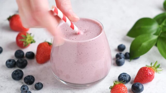 Berry fruit smoothie in glass with drinking straw. Healthy drink, pink smoothie or cocktail