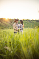 young beautiful couple, standing on a green meadow in the rays of the setting sun, cowboy clothes.rustic style