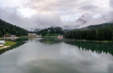 Panorama drone view of Lago di Misurina, reflection of the mountain in the lake, flying through the fog in the Dolomites in Italy
