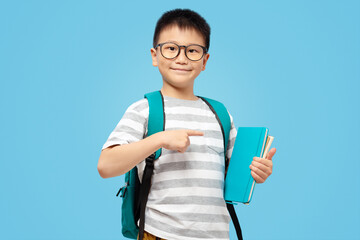 School kid with backpack holding and finger pointing at books