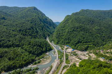 Fototapeta premium Cable-Stayed Bridge on the Adler-Krasnaya Polyana motorway. Aerial view of car driving along the winding mountain road in Sochi, Russia.