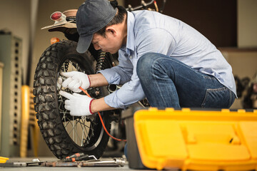 Obraz na płótnie Canvas Mechanic fixing motorbike in workshop garage, Man repairing motorcycle in repair shop, Repairing and maintenance concepts
