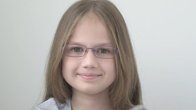 Portrait of beautiful happy little girl wearing stylish modern eyeglasses on light gray background. Children's vision corrective concept