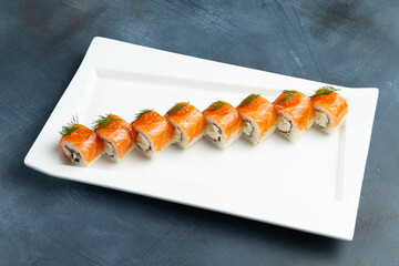 Rolls with salmon in a plate. On a gray background.