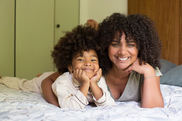 Smiling mother embracing her daughter in bedroom