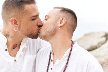 Close up photo of a gay couple kissing next to the sea