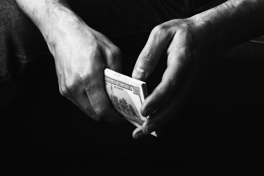 Male hands holding us hundred dollars banknotes. Man with american money closeup. Black and white photo