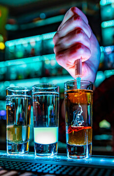 woman bartender hand making collection of colorful shots. Set of cocktails at the bar counter