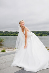 Fototapeta na wymiar Enchanting blonde bride in a wedding dress with a long beautiful veil. A tiara on her head
