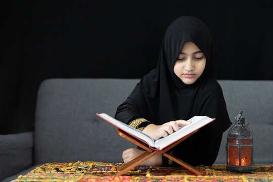 muslim girl reading a holy book or Quran on black background