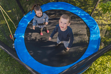 children jumping on a trampoline top view - obrazy, fototapety, plakaty