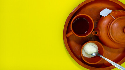 photo of a set of traditional clay teapots and teacups and a man's hand holding a cup, with a fresh yellow background and copy space to write a brand or a word about tea, shot at studio photo