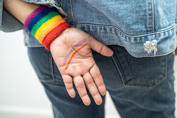 Asian lady wearing rainbow flag wristbands, symbol of LGBT pride month celebrate annual in June social of gay, lesbian, bisexual, transgender, human rights.